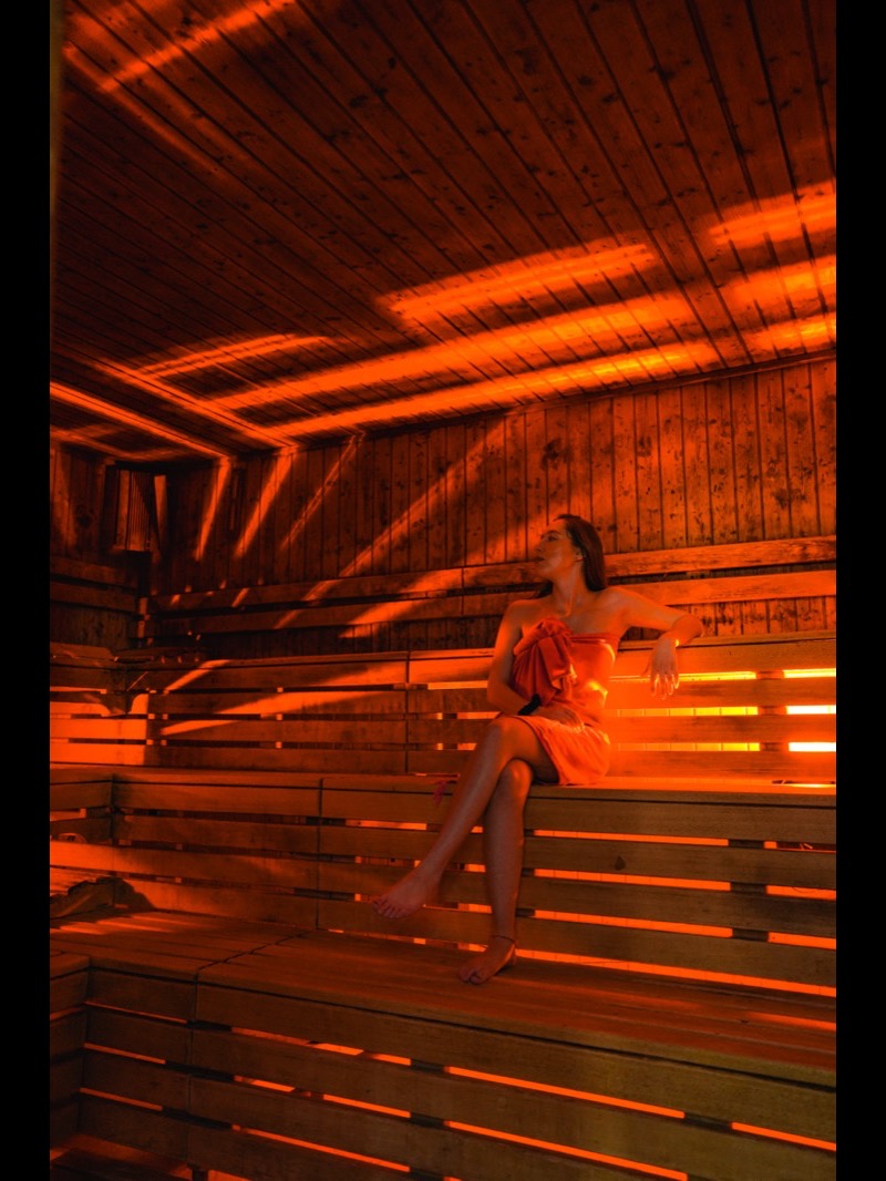 Una cliente nella sauna finlandese illuminata in arancione a La Sauna 1969